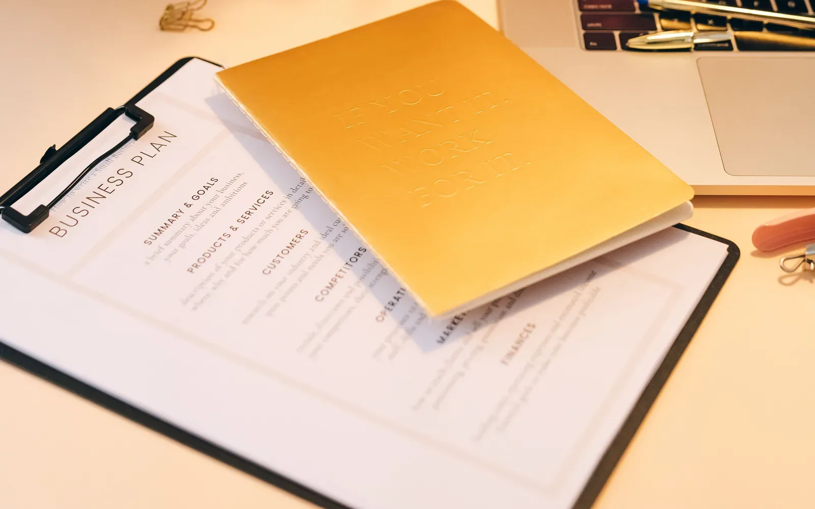 Documents, pens and an open laptop on a work desk.
